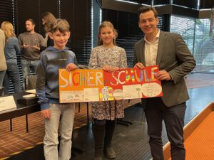 Zwei Kinder und ein Erwachsener halten ein Schild hoch